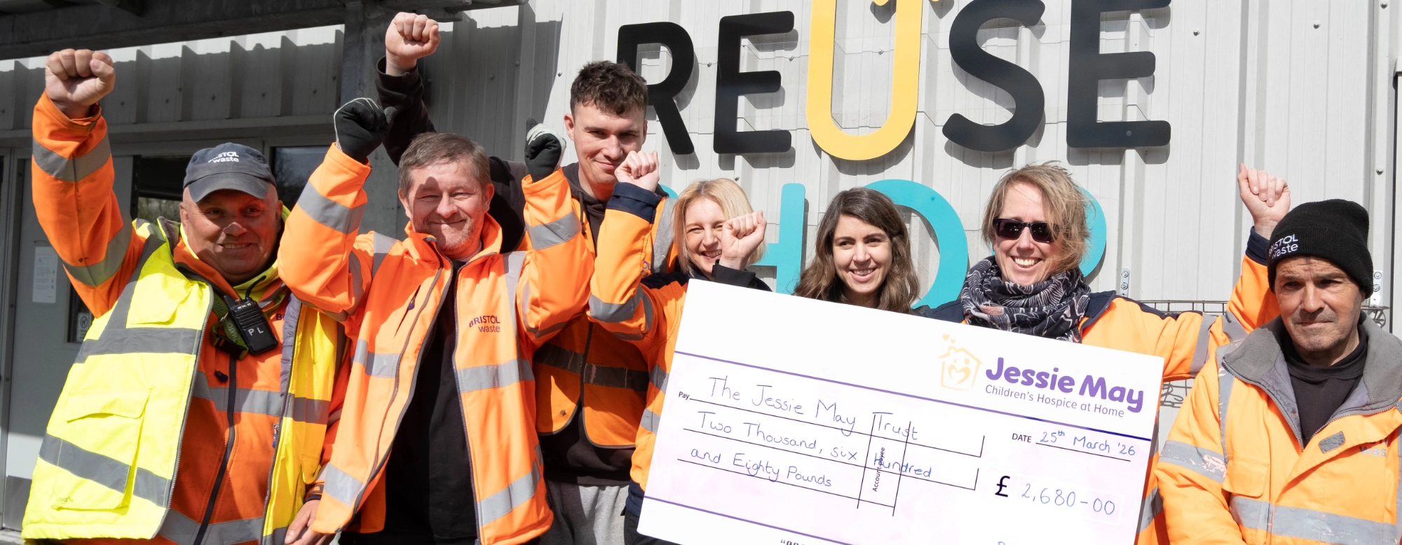 People in high-visibility clothing celebrating with a cheque for £2680 for Jessie May Trust