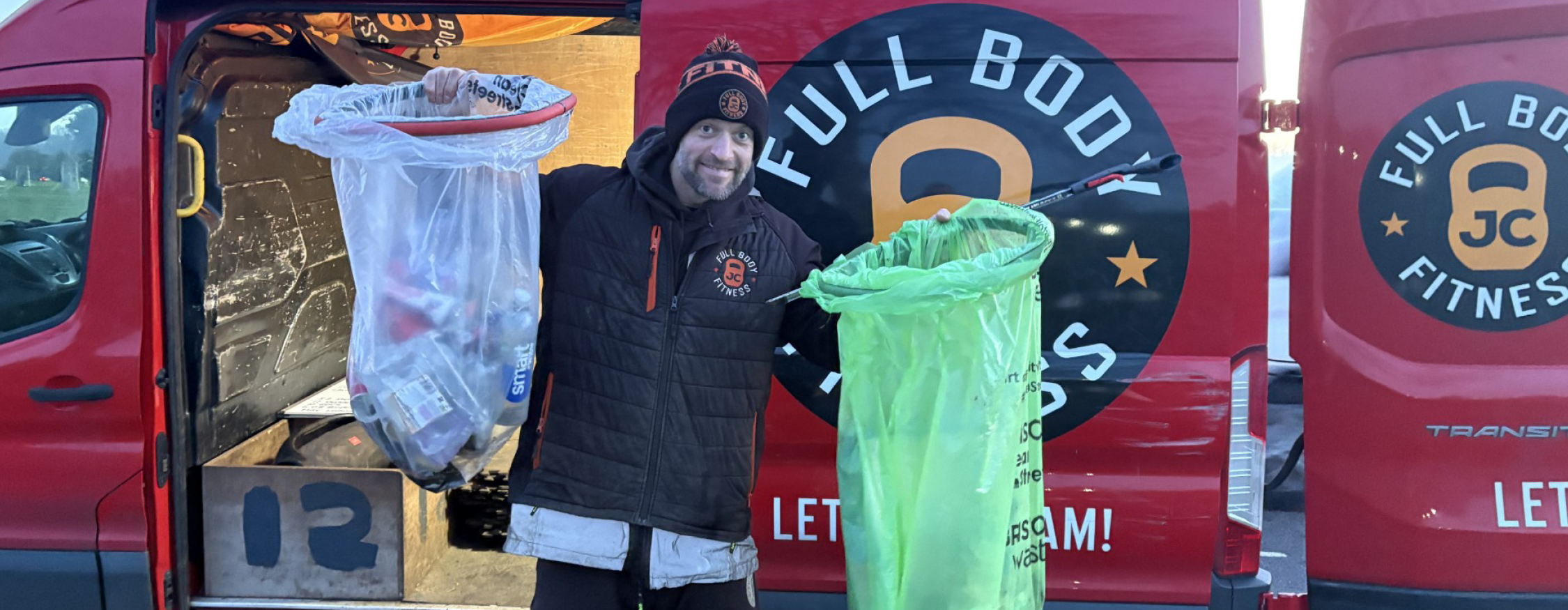 A smiling man in beanie hat and coat poses with litter picking bags next to a van with JC Full Body Fitness branding on the side